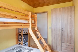 Una cama litera con escalera de madera, un armario y un mueble de almacenamiento con estampado de estrellas.