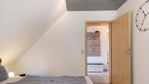 Ein Schlafzimmer mit einem Bett, einer Wanduhr und einer Tür zu einem Badezimmer.