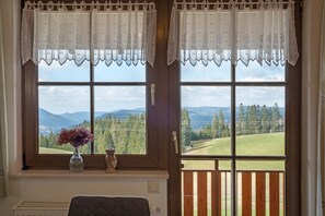 Una habitación con un ventanal grande, un jarrón con flores y un banco de madera.