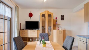 Ein Essbereich mit Tisch, Stühlen, einem Fernseher und einem Schrank.