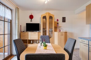 Un espace repas comprenant une table, des chaises, un téléviseur et un meuble.