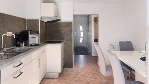 A modern kitchen with a built-in stove, a sink, and a dining area with a table and chairs. - Holiday Home 'Ferienhaus' with Private Terrace, Private Garden and Wi-Fi (Zernitz-Lohm)