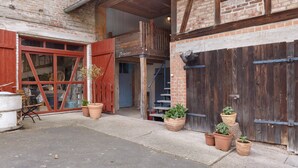 An outdoor area with a brick building, wooden doors, and potted plants. - Studio '30 sqm' with Wi-Fi in Historic Four-Sided Farmhouse (Friedewald)