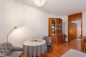Una sala de estar con una mesa redonda, dos sillas, un aparador y un sofá.