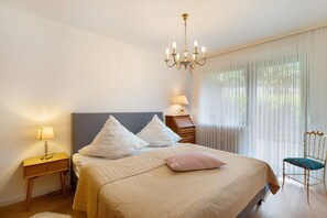Un dormitorio con cama, mesita de noche, lámpara, sillón y candelabro.