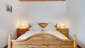 A wooden bed with a headboard, two bedside tables with lamps, and a picture on the wall. - Apartment '3' with Mountain View, Shared Garden and Wi-Fi (Hinterzarten)