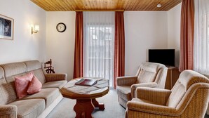 A room with a wooden ceiling, a sofa, two armchairs, a coffee table, a TV on a stand, and a window with curtains. - Apartment '3' with Mountain View, Shared Garden and Wi-Fi (Hinterzarten)