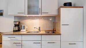 A modern kitchen with white cabinets, a stainless steel sink, and a coffee maker. - Apartment '3' with Mountain View, Shared Garden and Wi-Fi (Hinterzarten)