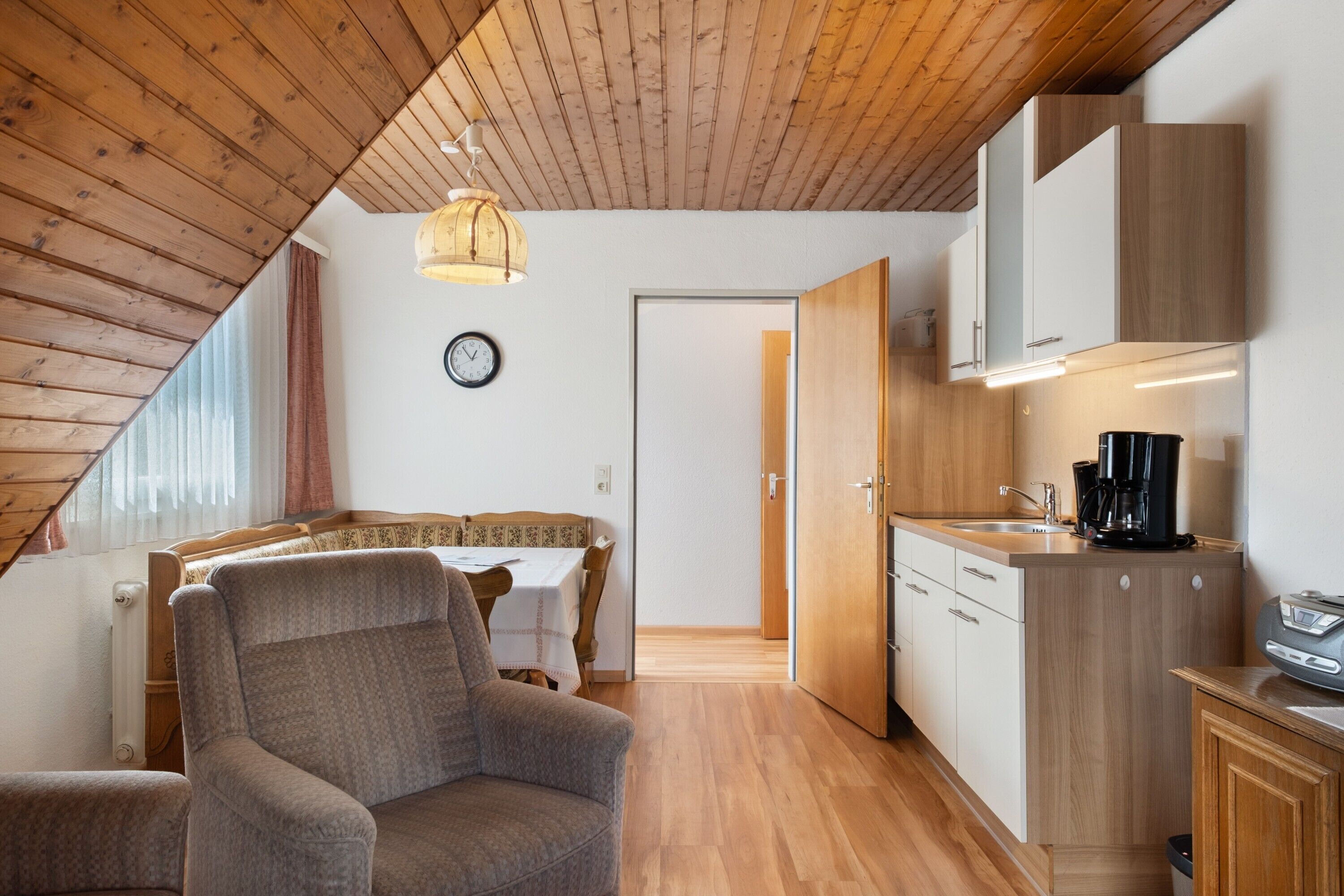 Una cocina moderna con armarios de madera, una zona de comedor con mesa y sillas, y un rincón de estar acogedor con sofá.