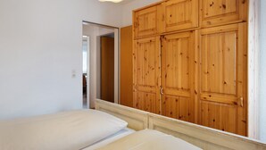 A bedroom with a wooden wardrobe, a bed with white bedding, and a light fixture above the bed. - Holiday Apartment '2' with Mountain View, Shared Garden and Wi-Fi (Hinterzarten)
