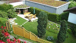 A residential garden with a patio, a wooden gate, and a green roofed structure. - Holiday Apartment '2' with Mountain View, Shared Garden and Wi-Fi (Hinterzarten)