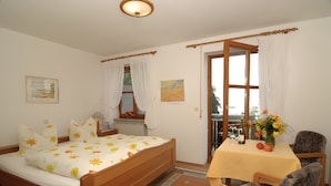 Un dormitorio con una cama de madera, una mesita con mantel amarillo y una silla.