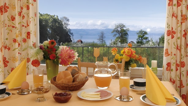 Una mesa dispuesta con alimentos para el desayuno, una jarra de jugo y vistas a las montañas.