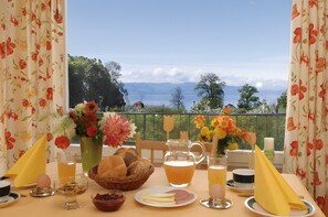 Ein Tisch reichhaltig gedeckt mit Frühstücksleckereien, ein Saftkrug und Blick auf die Berge.