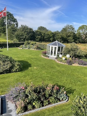 A well-maintained garden with a gazebo, a flagpole, and various plants.