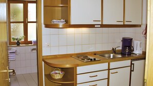 Une cuisine avec des armoires blanches, un plan de travail en bois, une machine à café et un évier.