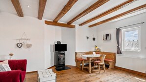 Une pièce chaleureuse avec un canapé rouge, une table à manger en bois et une cheminée.