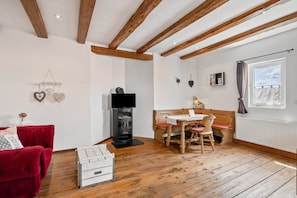 A cozy room with a red sofa, wooden dining table, and a fireplace.