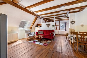 Um quarto estilo loft aconchegante com sofá vermelho, piso de madeira e vigas de madeira aparente.