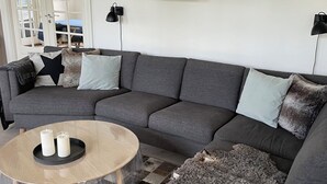 Un soggiorno con un divano grigio, un tavolino rotondo e un pavimento decorato.