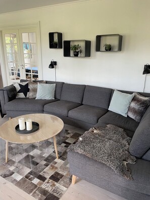 A living room with a grey sofa, a round coffee table, and a patterned floor. - Luxury country house in nature with wellness (Haderslev)