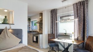 A compact living space with a bed, a dining table, and a kitchenette.