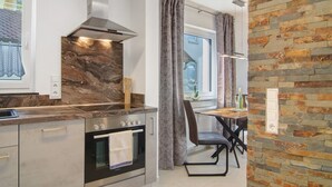 A modern kitchen with a built-in oven, a stove, and a marble backsplash.