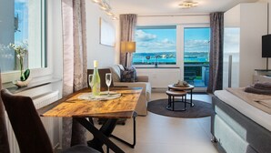 A modern room with a dining table, sofa, and a view of the sea.