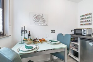 Et moderne køkken med spisebord til to, en mikrobølgeovn og et køleskab.