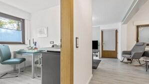 Eine moderne Küche mit Essbereich, einem kleinen Kühlschrank und einem Fenster mit Jalousien.