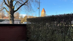 Ein überdachter Außenbereich mit Ziegelmauer, Baum und Hecke.