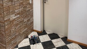 Un pasillo de hotel con un revestimiento de pared tipo piedra, una puerta con el letrero 'Por favor, no molestar' y un piso a cuadros.