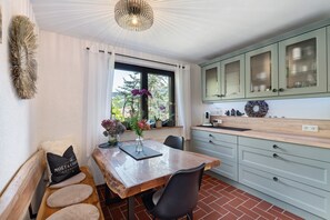 Una cocina con una mesa de madera, un banco y una ventana con cortinas.