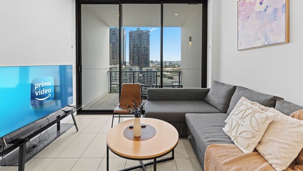 A modern living room with a flat-screen TV, a round coffee table, a sofa, and a chair. - Art House 2 King +Sofa Bed Free Parking Southbank (South Brisbane)