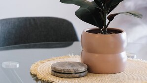 A glass table with a woven placemat, a potted plant, and a stone. - Art House 2 King +Sofa Bed Free Parking Southbank (South Brisbane)