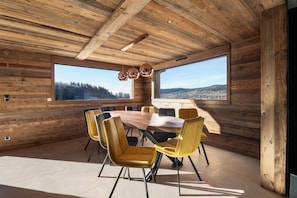 Ein Zimmer mit Holzvertäfelung, einem großen Tisch mit Stühlen, großen Fenstern und Blick auf eine Stadt.