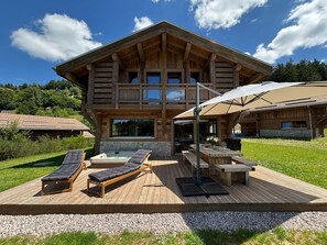 A wooden lodge with a deck, lounge chairs, and a hot tub. - Chalet Trevose⭐ Luxury • Hot Tub • Sauna • Close to the Slopes (Gerardmer)