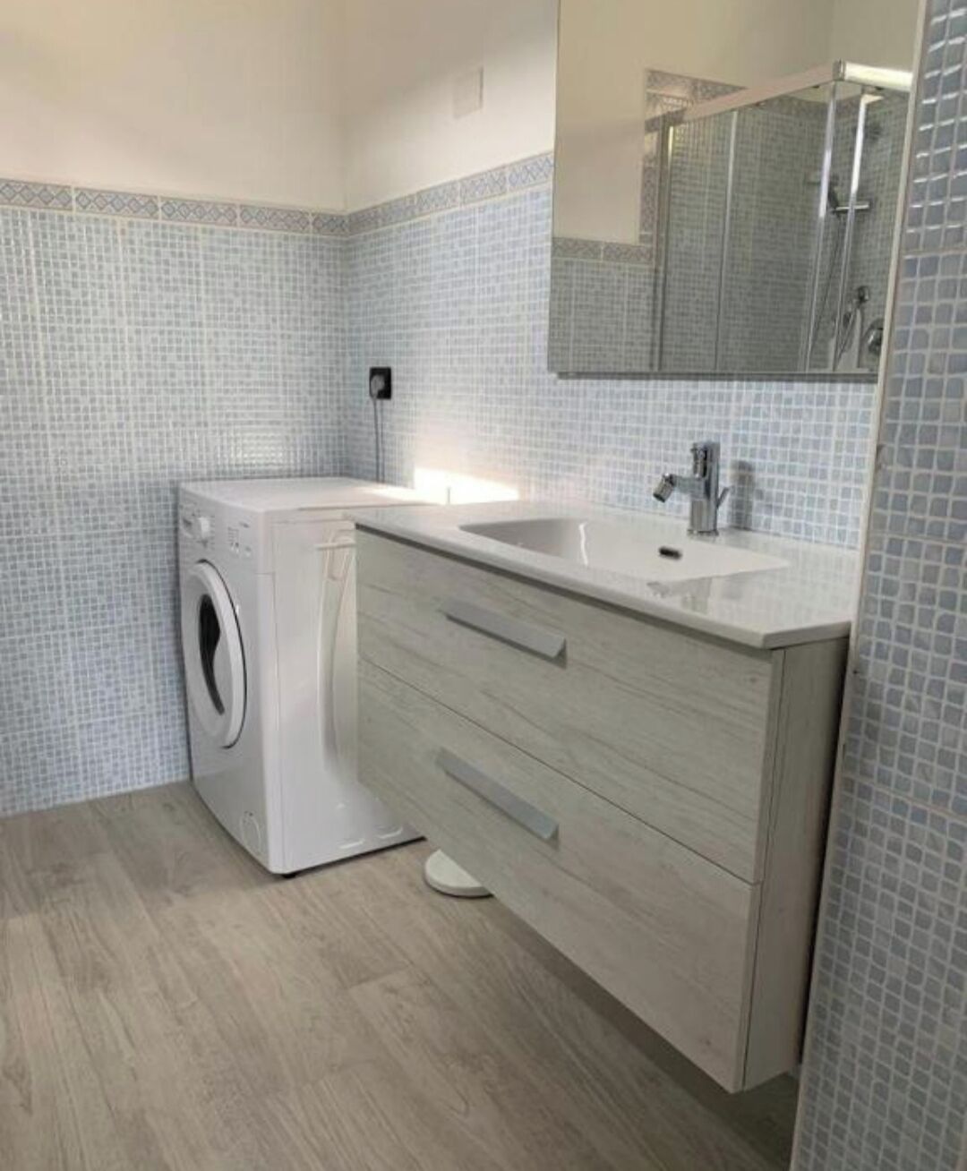 Ein modernes Badezimmer mit Waschmaschine, Waschbecken und Spiegel.