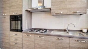 Een moderne keuken met inbouwapparatuur, een roestvrijstalen afzuigkap en een gootsteen met kraan.