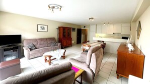 A living room with a sofa, coffee table, TV, and wooden cabinet. - Apartment by Belgian Coast with Sea View (MIDDELKERKE)