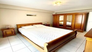 A bedroom with a large bed, wooden wardrobe, and a nightstand. - Apartment by Belgian Coast with Sea View (MIDDELKERKE)