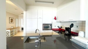 A modern kitchen with white cabinets, a stainless steel sink, a microwave, and a coffee maker.