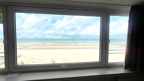 A room with a large window overlooking a beach.