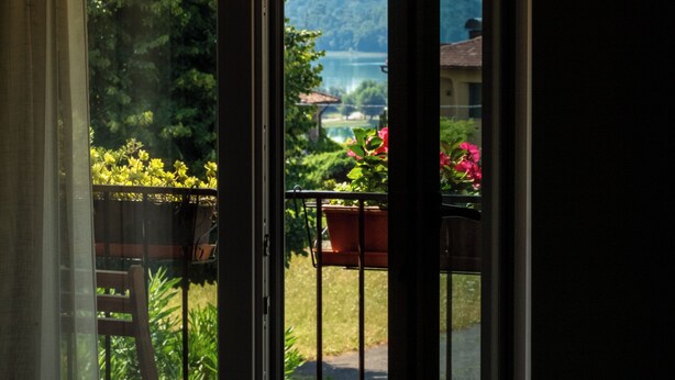 Vista da un balcone con ringhiera, una sedia e una pianta in vaso.