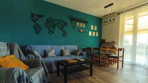 Un soggiorno con un divano blu, un tavolino da caffè e un'area pranzo con sedie e tavolo in legno.