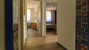 Un corridoio con pavimento in legno, una tenda blu e una parete rivestita di piastrelle colorate.
