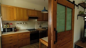 Una cucina con mobili in legno, un forno a microonde, un fornello e un lavandino.