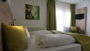 A hotel room with a bed, a chair, a television, and a painting on the wall. - Berger's Bergsicht by edita (Scheidegg)