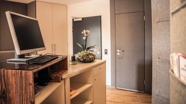 A modern office space with a wooden desk, a computer, and a vase with flowers. - Berger's Bergsicht by edita (Scheidegg)