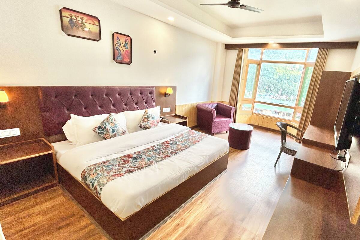 A hotel room with a large bed, a chair, a desk, and a television.